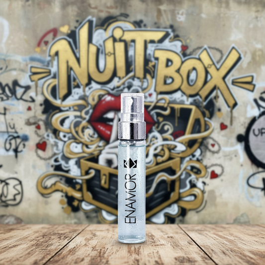 Perfume Enamor sobre mesa de madera, mural Nuit Box de fondo, sex shop Quilpué